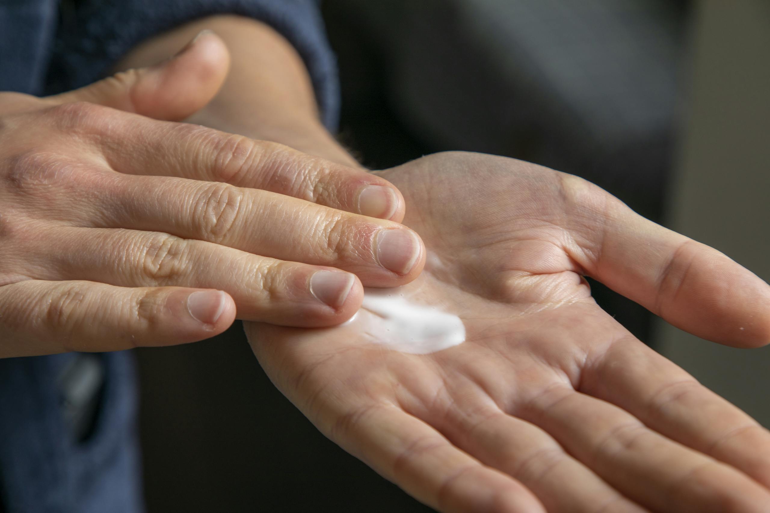 Detailed view of hands applying cream for skincare use.