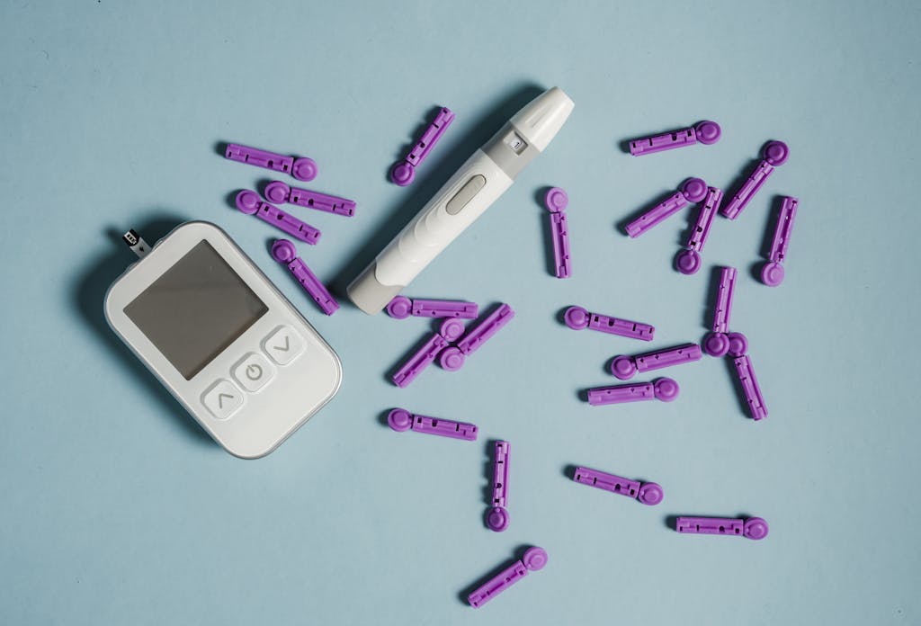 Flat lay of a blood glucose meter with lancets and lancing device on a blue background.
